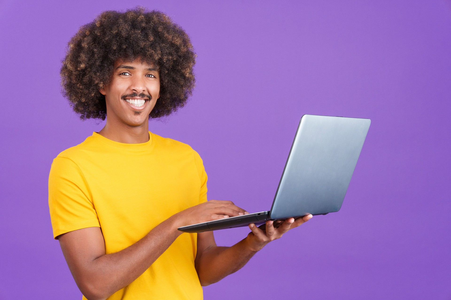 Smiley african man standing and using a laptop